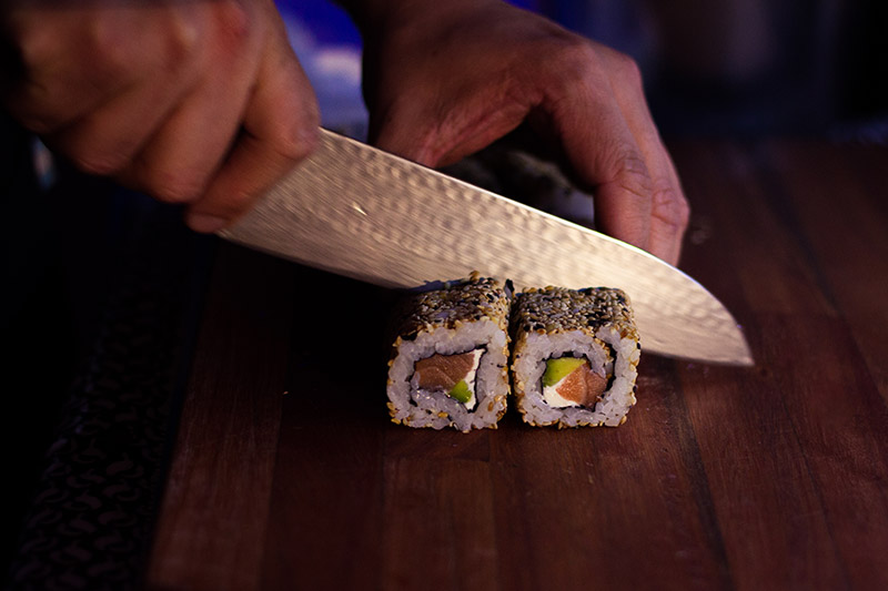 Närbild på en kock som skär upp sushi